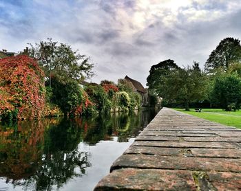 View of footpath in park against cloudy sky