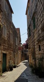 Empty alley amidst buildings against sky