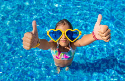 Portrait of girl wearing novelty glasses in pool