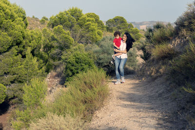 Woman with her child in her arms walking through the countryside far from the city