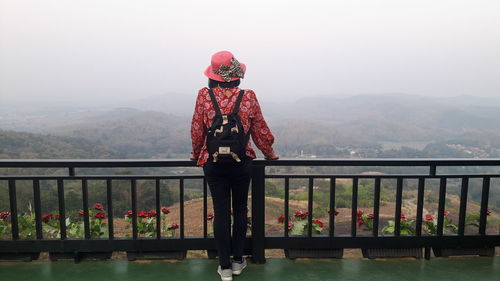 Man standing on railing against mountain