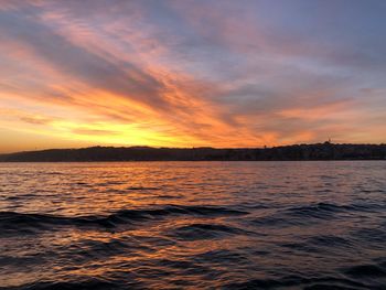 Scenic view of sea against dramatic sky during sunset