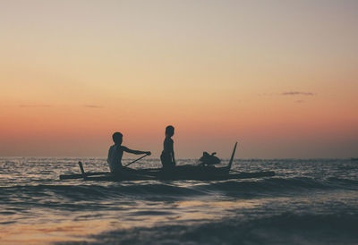 Silhouette people on beach against sky during sunset