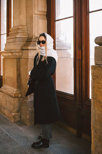 Portrait woman wearing sunglasses standing against door