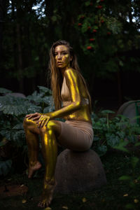 Young woman with golden skin sitting in the garden