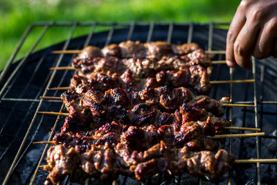 Cropped hand cooking meat on barbecue