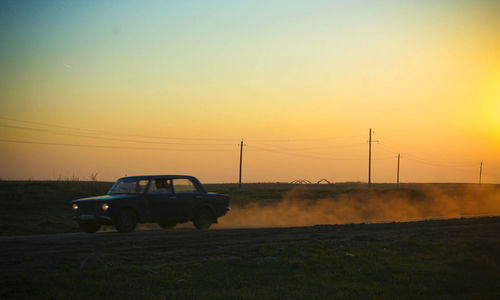 Car on land against sky during sunset