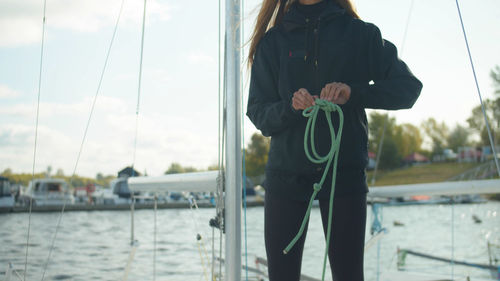 Rear view of man holding sailboat in river