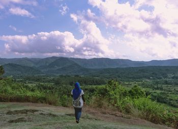 Rear view of man standing on land against sky