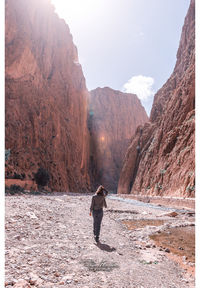 Rear view of man standing on mountain against sky