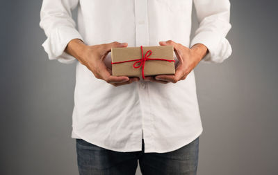 Midsection of man holding box against white background