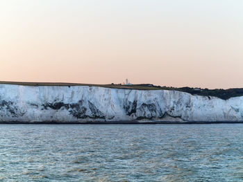 White cliffs by sea against clear sky