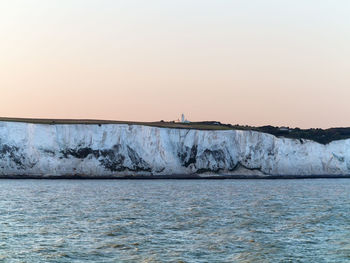 White cliffs by sea against clear sky