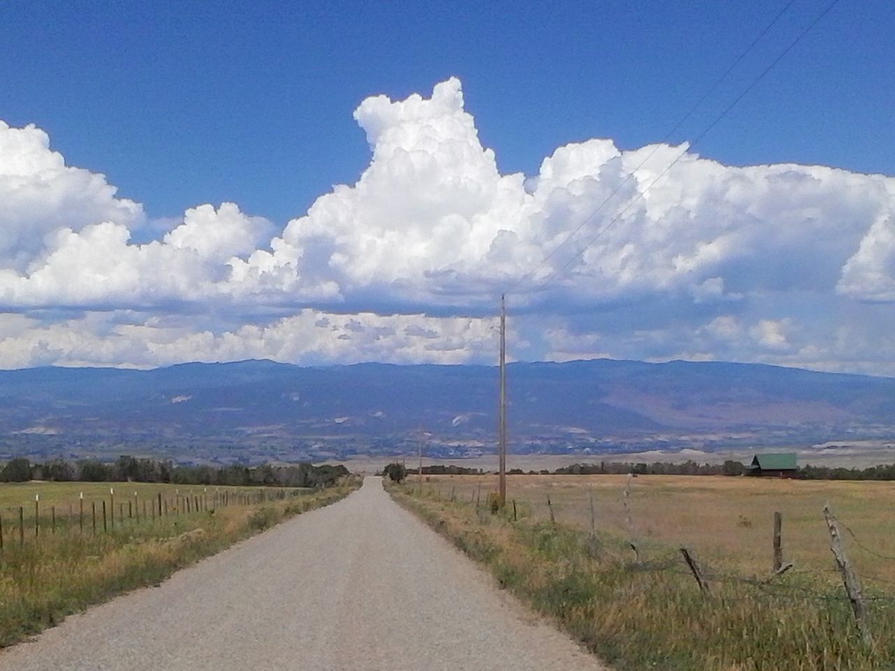 the way forward, sky, landscape, road, tranquil scene, field, diminishing perspective, tranquility, electricity pylon, cloud - sky, cloud, blue, rural scene, country road, vanishing point, scenics, transportation, mountain, nature, power line