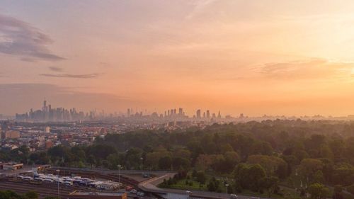 Cityscape and trees against sky during sunset