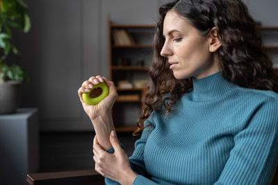 Female office worker exercising with hand grip at workplace for strengthening wrist and forearm