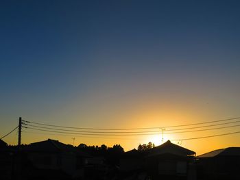 Silhouette houses against sky during sunset