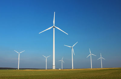 Wind turbines on field against clear sky