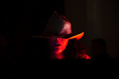 Close-up of woman wearing hat in dark