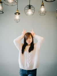 Portrait of woman standing against illuminated lamp