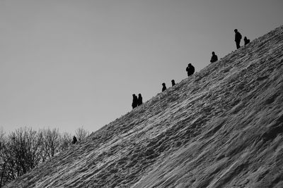 Low angle view of people on land against clear sky