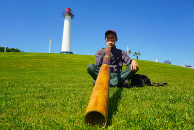 Portrait of man playing wind instrument while sitting on grassy land