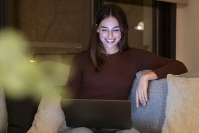 Portrait of young woman sitting on sofa at home