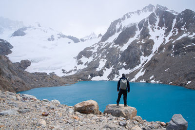 Rear view of man standing on rocks against mountain