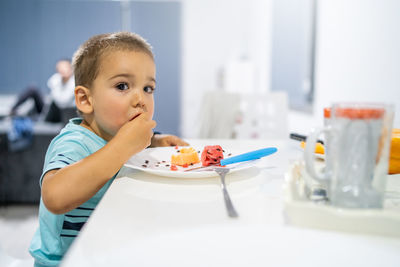 Close-up of boy eating fruits on table at home