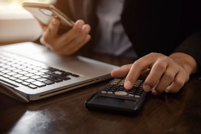 Midsection of woman using calculator at table