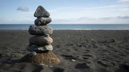 Stack of pebbles on beach against sky