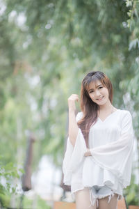 Young woman standing against plants