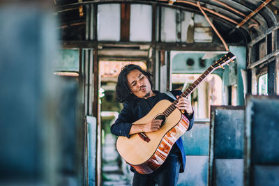 Young guitarist playing guitar in bus