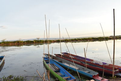 Sailboats moored in lake against sky