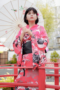 Portrait of smiling young woman standing in city