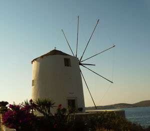 Traditional windmill by sea against clear sky