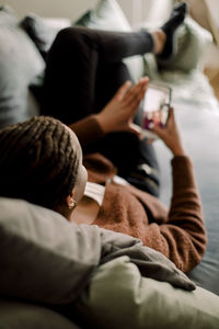 Full length of teenage girl using smart phone while lying on sofa at home
