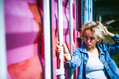 Woman standing by wall in sunny day