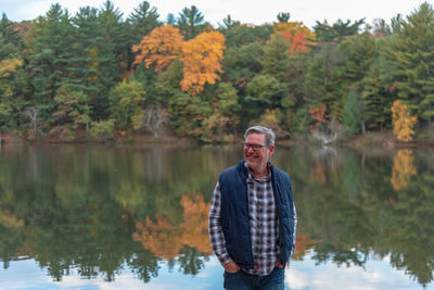 Smiling man standing against lake during autumn