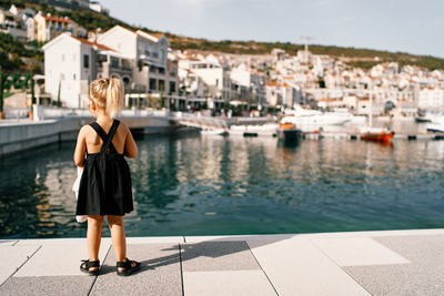 Rear view of young woman standing by lake