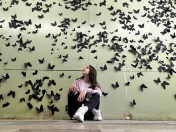 Full length of woman sitting against wall