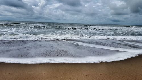 Scenic view of beach against cloudy sky