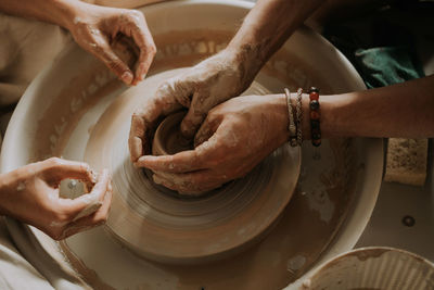 Potter teach teenage girl working with pottery wheel. top view. close up.