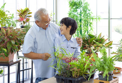 Grandfather and grandson standing by plants in greenhouse