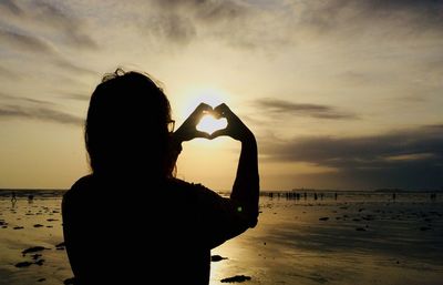 Rear view of silhouette woman at beach during sunset