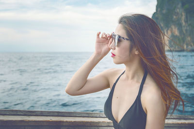 Beautiful young woman wearing sunglasses while sitting in boat on sea