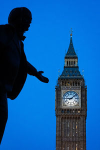 Low angle view of silhouette man standing against blue sky