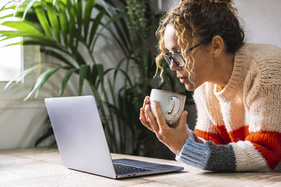 Young woman using laptop while sitting on table