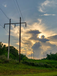 Electricity pylon on field against sky during sunset