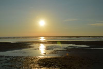 Scenic view of sea with sunlight reflection at sunset